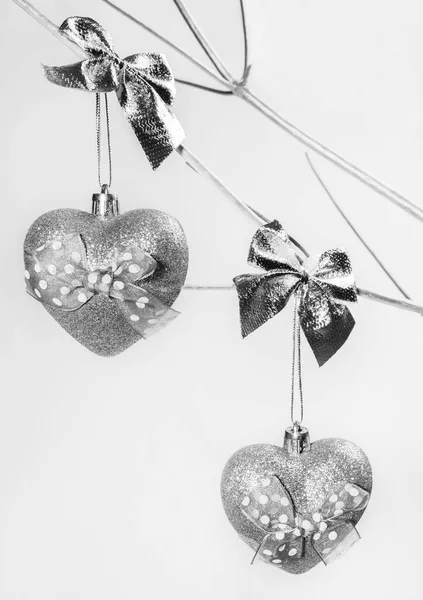 Zwei Weihnachtsspielzeuge silbern funkelnde Herzen auf Zweigen alternativer Weihnachtsbäume aus trockenem Holz in Silber lackiert. — Stockfoto
