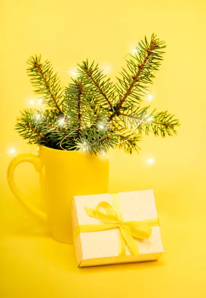 Composición de Navidad de invierno en color amarillo - ramas de abeto en taza, luces de Navidad, caja de regalo de bricolaje. — Foto de Stock