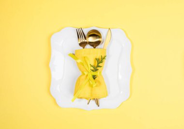 Altın çatal bıçak seti, kaşık, peçeteye sarılı çatal, yeşil arborvitae dalı, beyaz şekilli tabakta sarı. Xmas tebrik kartı ya da davetiye. Boşluğu kopyala.