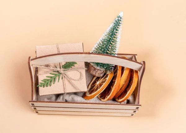 Vista desde arriba a la caja de madera con árbol de Navidad decorativo, rebanadas de naranja seca y caja de regalo en beige. — Foto de Stock