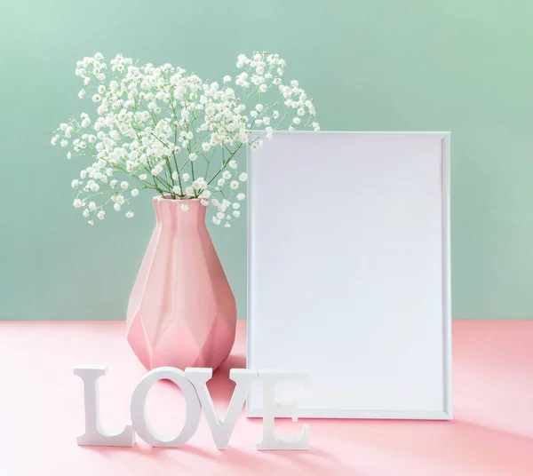 Vazoda Gypthe ile yaratıcı kart, boş beyaz çerçeve, beyaz harfler Pastel pembe-yeşil üzerinde aşk.
