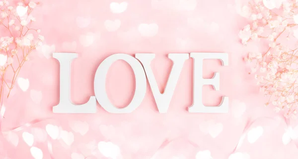 Lettere bianche LOVE con cornice di gipsofila bianca gentile su rosa pastello con luci bokeh cuori. — Foto Stock