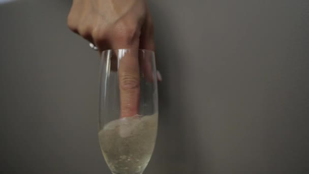 A beautiful woman stirs champagne in a glass with her finger — Stock Video