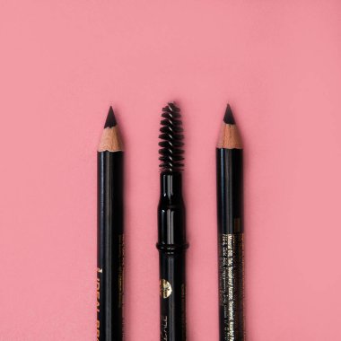 Makyaj ürünü, pembe arka planda rimel sürmüş dudak kalemi.