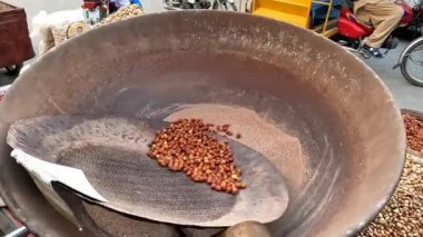 Siyah bezelyeler sıcak kumda, yol kenarı Pakistanlı ve Hint sokak yemeklerinde ısıtılıyor.