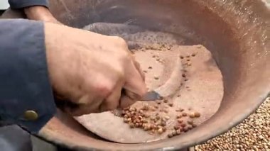 Nohut, yol kenarındaki Pakistan ve Hint yemeklerini ısıttıktan sonra nohut ve kumu filtrelemek veya ayırmak