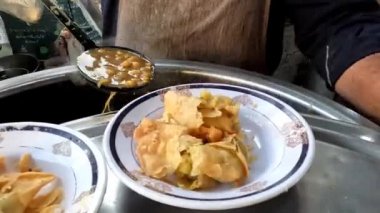Yol kenarı tezgahı, adam samosa chaat içine nohut ya da chanay ekliyor, Pakistan Hint sokak yemekleri