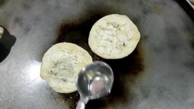Sokak yemekleri satıcısı mangırı hazırlıyor ve kızartılmış paratha roti 'yi kızgın yağda pişiriyor..