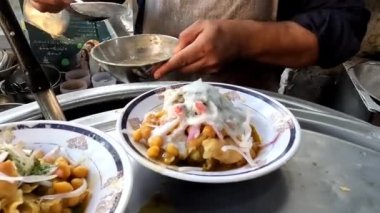 Samosa sohbetine yoğurt koymak, sıcak samosa ile doldurulmuş tabak ve pişmiş nohut, hindiba ve soğan, Pakistanlı ve Hint sokak yemekleri