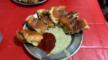 Kırmızı masa 4K yüksek çözünürlüklü video üzerinde ketçap ve yeşil nane soslu çalma tabağı içinde ve suni hamburgerin yakın görüntüsü