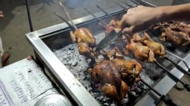 Tükürükte kızartılmış tavuk, parlak kayın kömürlerinin üzerinde kızartılıyor. Baharat fırçasıyla bütün tavukları ızgaraya çeviriyor.