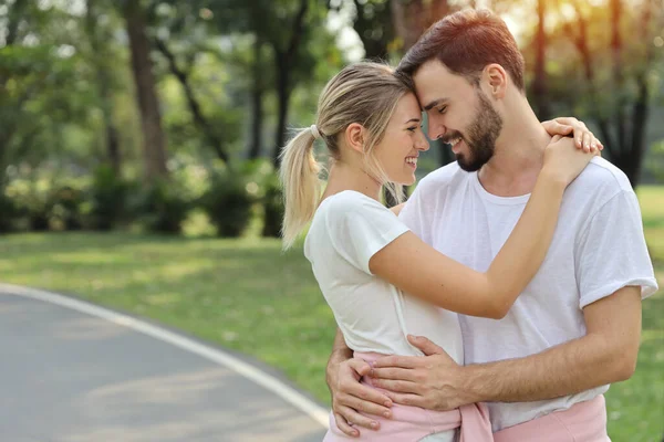 年轻的白种人夫妇相爱了男人和女孩穿着白色衬衫拥抱在公园在夏季与微笑和幸福的脸 — 图库照片