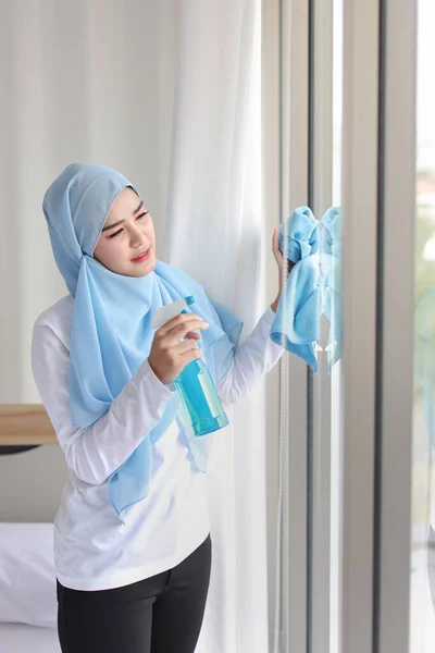 室内射精的年轻漂亮的亚裔穆斯林家庭主妇拿着清洁剂 洗窗玻璃 搬进新公寓后 带着快乐的情绪清洁卧室的可爱的画像女孩 — 图库照片