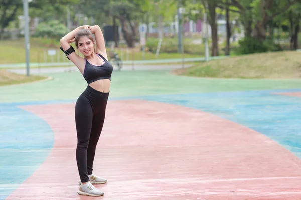 スポーツウェアの若い健康と美しさのアジアの女性が立って 朝の運動のために屋外でストレッチ アクティブガールは 携帯電話でバイク練習に取り組んでいます スポーツとライフスタイルのコンセプト — ストック写真