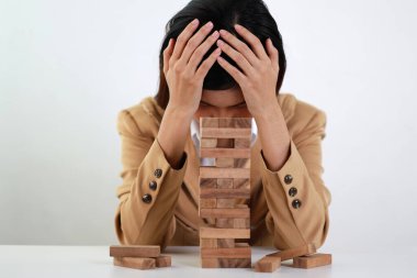 Klasik süitteki iş kadını kafasına dokunuyor ve oturuyor, tahta blok dominoları üzerine yüzüstü yatıyor. Yatırım Sigortası veya iş riski kontrol kavramı