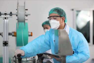 Müfettiş erkek ve iş arkadaşı maske ve tıbbi yüz maskesi üretim hattı, endüstri ve fabrika konsepti üzerinde çalışıyor..