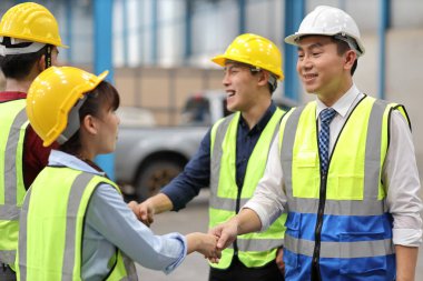 Koruma üniformalı bir grup mühendis birlikte başarılı bir şekilde el sıkışıyor ya da endüstri deposu imalat fabrikasındaki anlaşma taahhütlerini başarıyla yerine getiriyor.