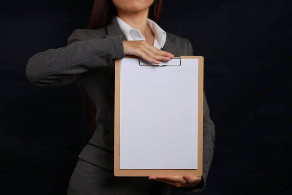 Привлекательные профессиональные женские руки стоя и показывая чистый лист бумаги для рекламы на черном фоне изолированы