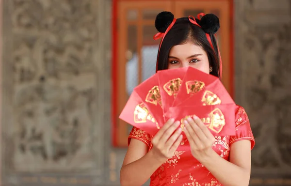 赤い中国のドレスの美しいアジアの女性赤い封筒やエキサイティングな感情を持つ任意のパオを示すジェスチャーで伝統的なChongsam Qipao テキストは家に入る幸運を意味します 中国の新年 — ストック写真