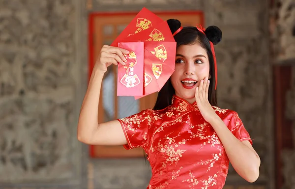 Kırmızı Çinli güzel bir kadın geleneksel Cheongsam Qipao 'nun kırmızı zarf ya da heyecan verici duyguları olan herhangi bir Pao' nun jesti, mesaj eve girerken iyi şanslar demektir (Çin yeni yılı).)