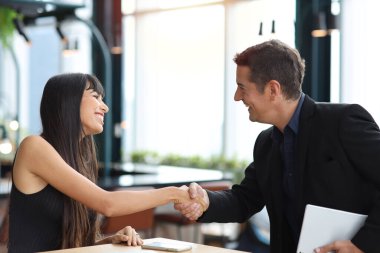 Yeni iş sözleşmesi imzalandıktan sonra mutlu yüzlü bilgisayar ve akıllı cep telefonu kullanarak iş birlikçi iş adamlarının el sıkışma süreci. İş arkadaşı ve birlikte çalışma kavramı