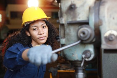 Güvenlik önlemi alan koruyucu üniformalı bir mühendis ya da işçi kadın ya da ağır sanayi imalat fabrikasındaki torna makinesini kontrol eden. Metal çalışma kavramı