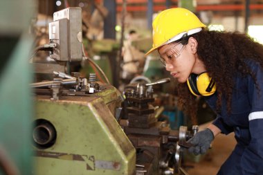 Güvenlik önlemi alan koruyucu üniformalı bir mühendis ya da işçi kadın ya da ağır sanayi imalat fabrikasındaki torna makinesini kontrol eden. Metal çalışma kavramı
