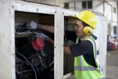 Koruma üniformalı mühendis veya işçi ayakta ve onarım veya ağır sanayi imalat fabrikasında güvenlik başlığı ile endüstri makine süreci kontrol