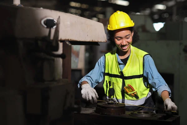 Happy technician engineer in protective uniform standing and using measure ruler while repairing operation or checking industry machine process with hardhat at heavy industry manufacturing factory