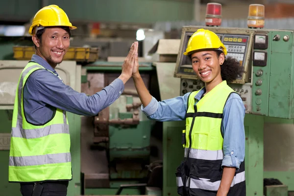 Happy smiling teamwork technician engineer or worker in protective uniform with hardhat give high five celebrate successful together completed deal commitment at heavy industry manufacturing factory