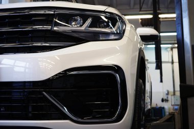 Modern lüks bir arabanın önünü kapatın. Arka planda bir araba servisi var. Arka plan bulanık. Seçili odak.