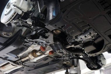 Araba servisindeki modern araba asansörde. Arabanın alt manzarası. Seçili odak, arkaplan bulanıklaştırıldı. Araba servisi, yedek parça, vücut onarımı..