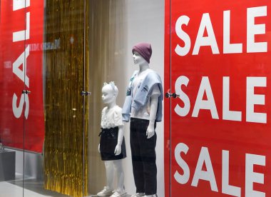 Moscow Russia - January 2022: In the window of a fashionable clothing store there are mannequins and a bright inscription SALE. Seasonal sale at reduced prices. Advertising.