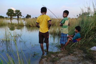 A few rural children growing up in the lap of nature are fishing from the river with the fishing rod
