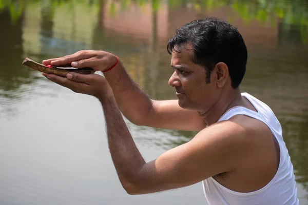 一个印度印度教年轻人在河岸上向太阳鞠躬 手里拿着一个Kosha Kushi 印度教中崇拜太阳神的方法 — 图库照片