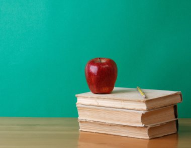 bir kalem ve bir yığın kitap üzerinde kırmızı elma