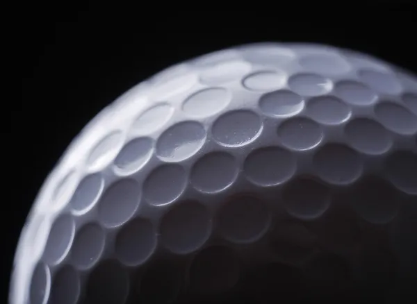 Um close-up de uma bola de golfe sobre fundo escuro — Fotografia de Stock
