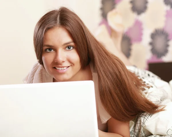 Eine junge Frau mit Laptop auf dem Bett liegend — Stockfoto