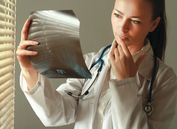 La mujer está de pie cerca de la ventana y examinando rayos X —  Fotos de Stock