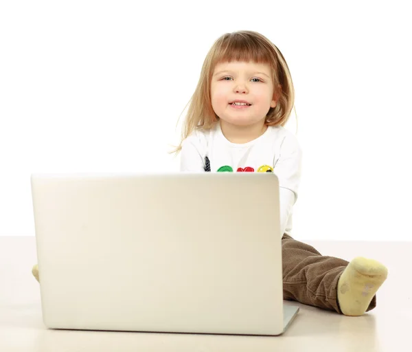 Ein kleines Mädchen mit einem Laptop auf dem Boden — Stockfoto