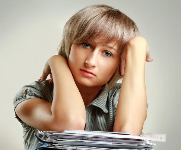 En trött ung kvinna sitter vid skrivbordet — Stockfoto