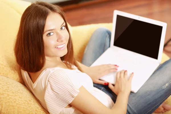 Mujer trabajando en una laptop sentada en un sofá —  Fotos de Stock