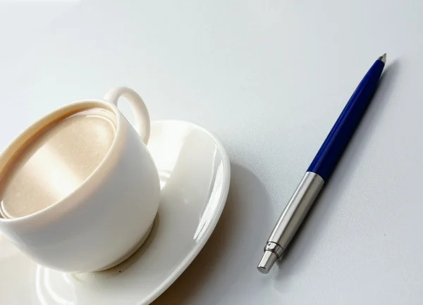 Šálek kávy a pero na stůl — Stock fotografie