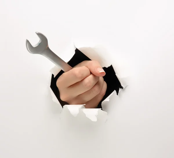 Een vrouwelijke hand met een moersleutel — Stockfoto