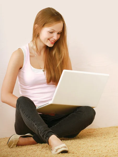 Bir dizüstü bilgisayar ile katta oturan genç kadın portresi. — Stok fotoğraf