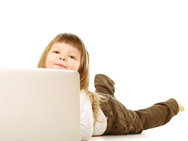 Une petite fille avec un ordinateur portable couché sur le sol — Photo