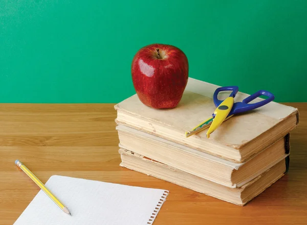 Red apple and scissors on pile of books — Stock Photo, Image