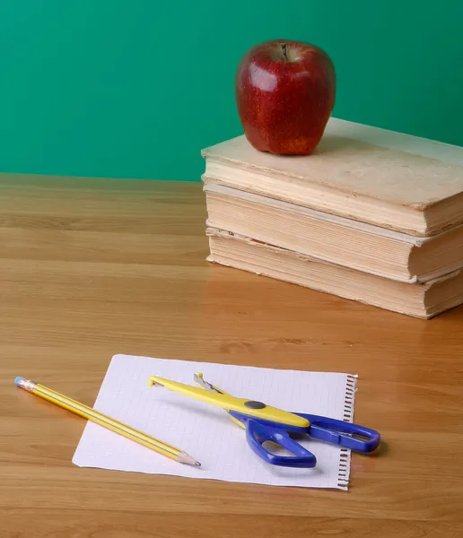 Manzana roja y tijeras en un montón de libros — Foto de Stock