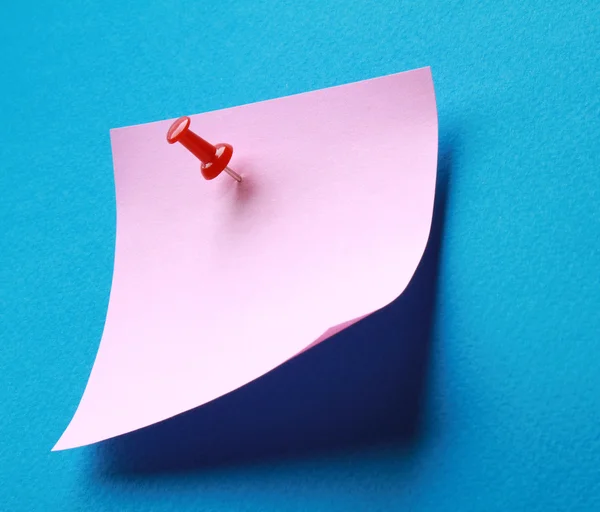 Pink paper note on blue background isolated. — Stock Photo, Image
