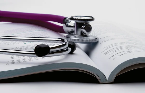 A stethoscope is lying on an open book — Stock Photo, Image